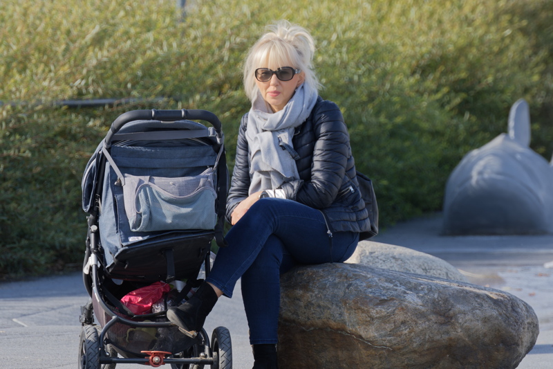14 - A person sitting on a rock next to a stroller in a park